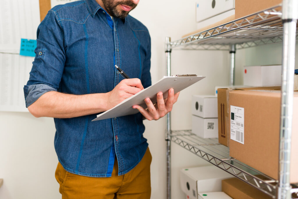 Logistics planner with a lot of orders at his online shop. Business owner writing customers' information on a clipboard