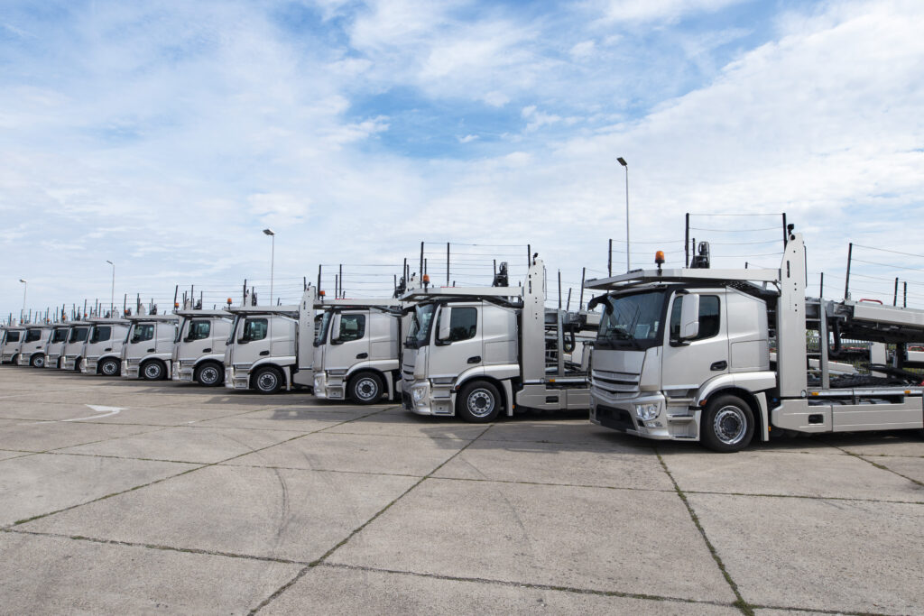 Group of trucks parked in line at truck stop.