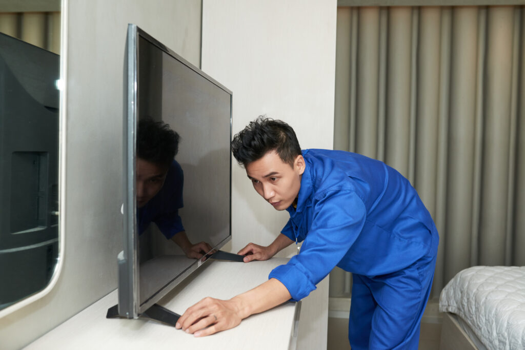 Courier applying the white glove delivery method and  installing television in a bedroom of a customer